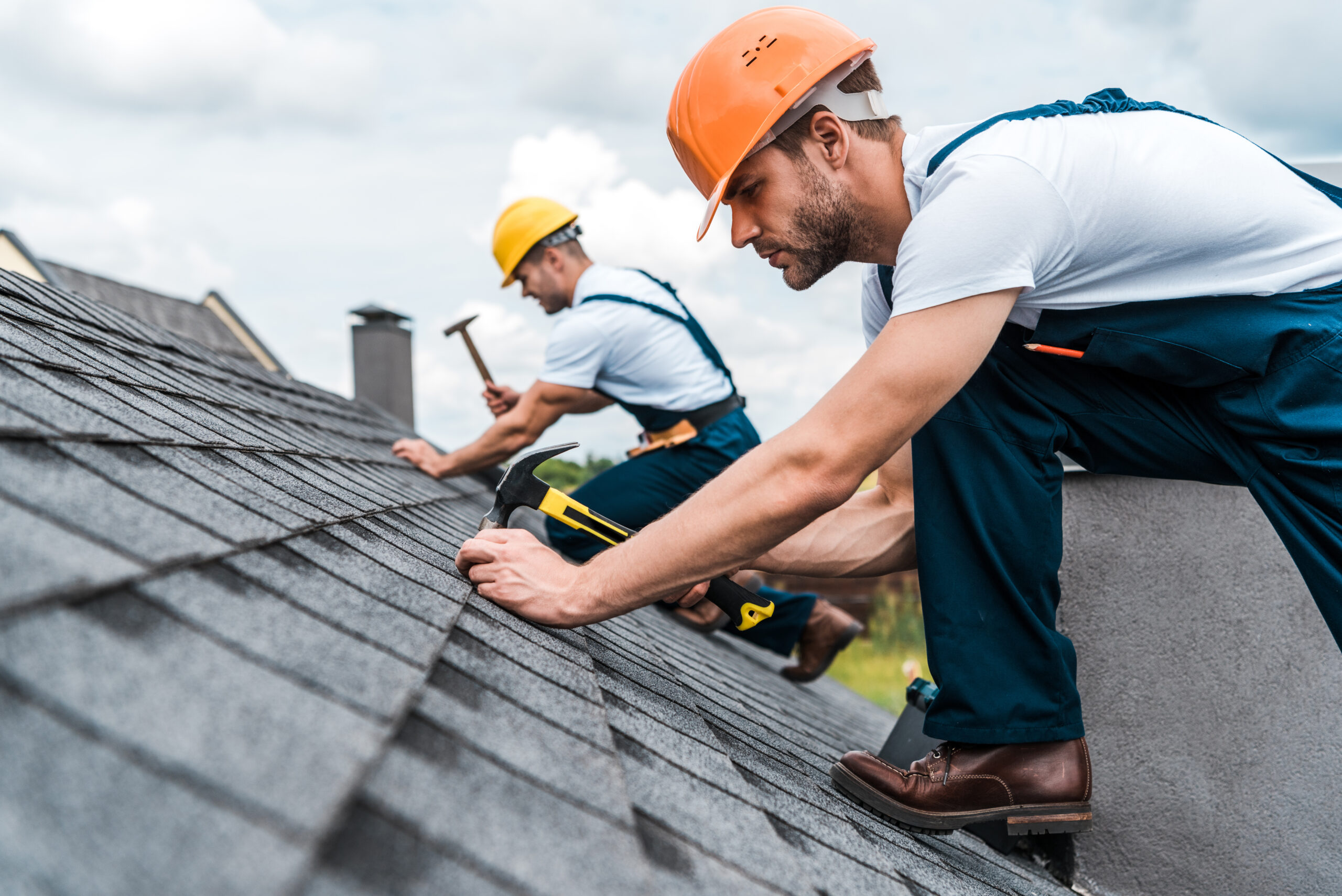 two workers installing roofing onto a home