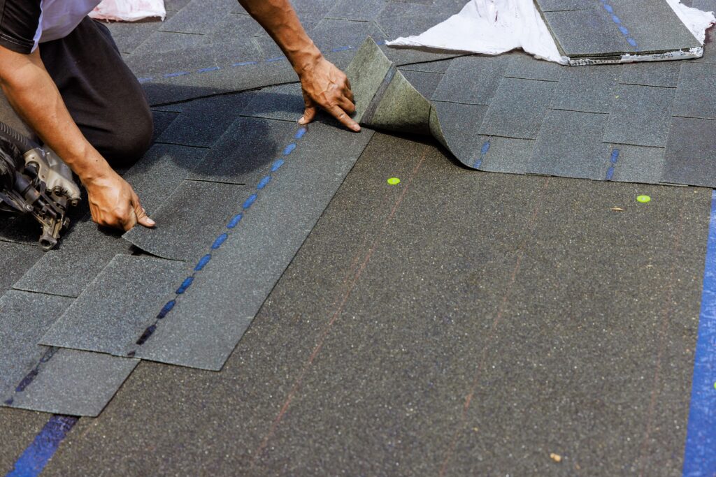 roofer layering shingles on roof