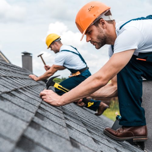 two workers installing roofing onto a home