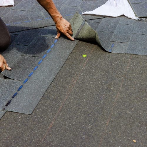 roofer layering shingles on roof